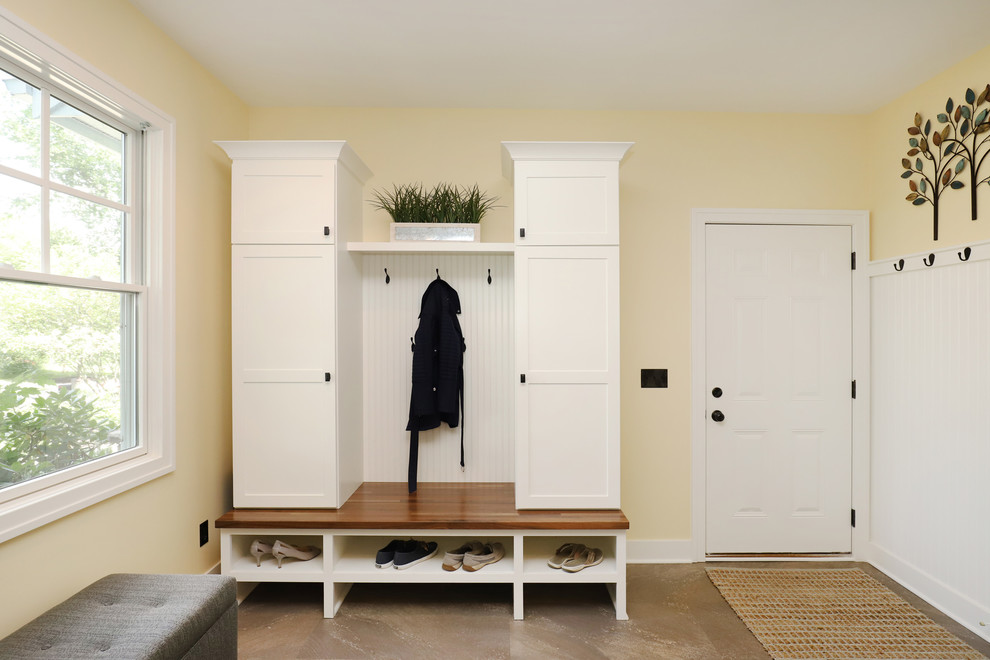 Design ideas for a mid-sized traditional galley utility room in Grand Rapids with shaker cabinets, white cabinets, laminate benchtops, yellow walls, laminate floors, a side-by-side washer and dryer and beige floor.