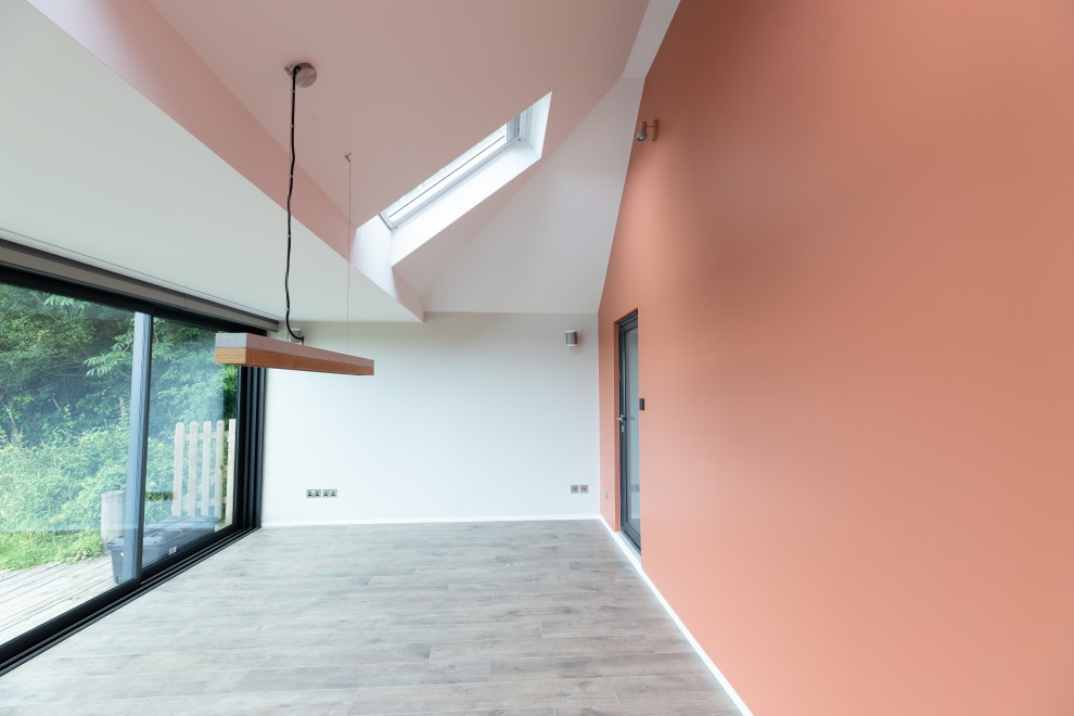 Cette image montre une salle à manger ouverte sur la cuisine minimaliste de taille moyenne avec un mur rouge, un sol marron et éclairage.