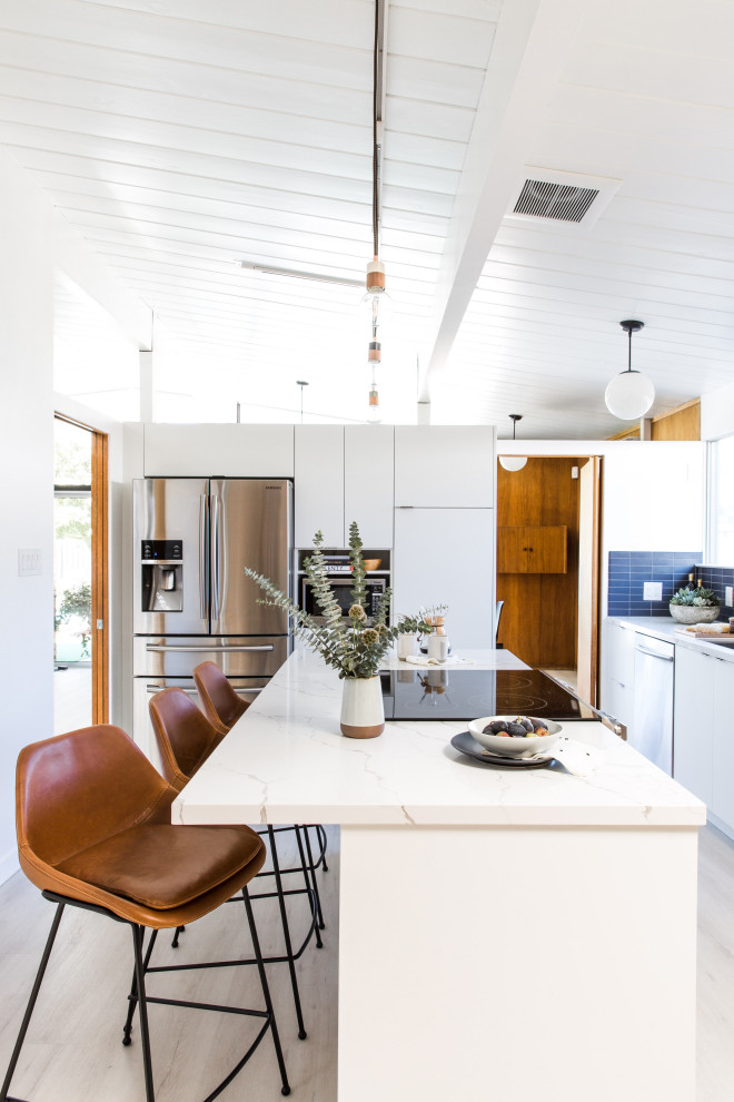 Inspiration for a mid-sized midcentury l-shaped kitchen in San Francisco with an undermount sink, flat-panel cabinets, white cabinets, quartz benchtops, blue splashback, ceramic splashback, stainless steel appliances, vinyl floors, with island, white benchtop and exposed beam.