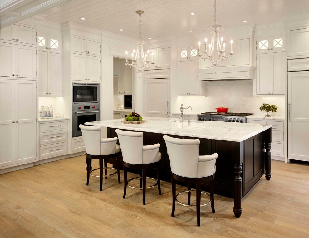 Design ideas for a large traditional l-shaped open plan kitchen in San Francisco with white cabinets, marble benchtops, white splashback, light hardwood floors, with island, shaker cabinets, panelled appliances, a farmhouse sink and ceramic splashback.
