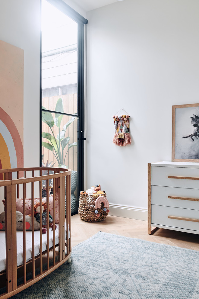 Photo of a contemporary nursery in Melbourne with white walls, light hardwood floors and beige floor.