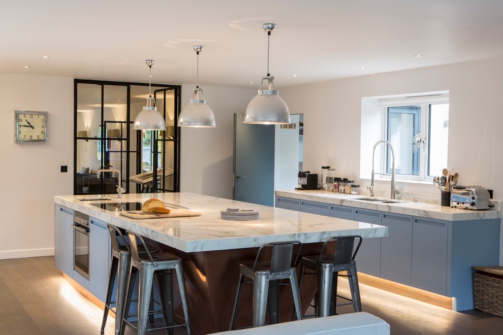 Inspiration for a contemporary kitchen in Surrey with blue cabinets and with island.
