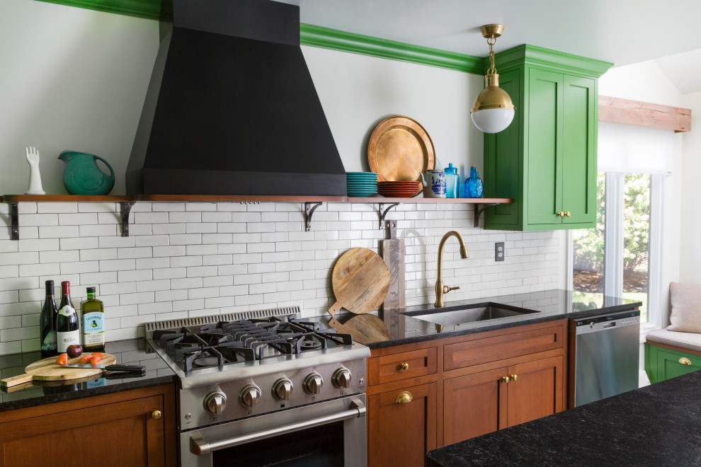 Inspiration for a mid-sized eclectic l-shaped eat-in kitchen in Philadelphia with an undermount sink, shaker cabinets, green cabinets, granite benchtops, white splashback, ceramic splashback, stainless steel appliances, slate floors, with island, green floor and black benchtop.