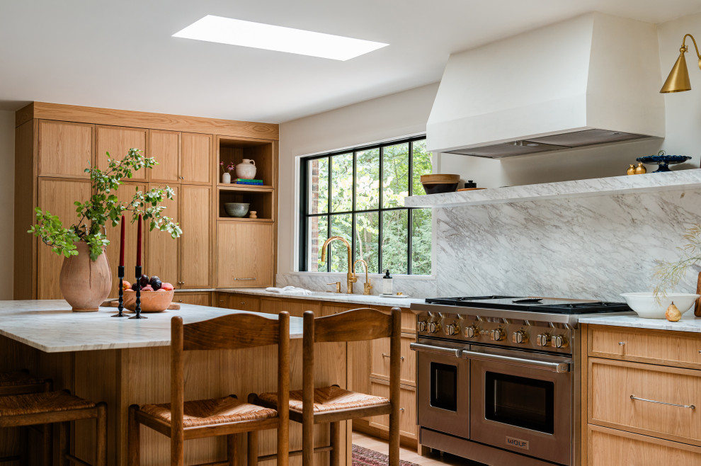 Mid-sized transitional l-shaped light wood floor eat-in kitchen photo in Chicago with an undermount sink, shaker cabinets, light wood cabinets, marble countertops, white backsplash, marble backsplash, paneled appliances, an island and white countertops