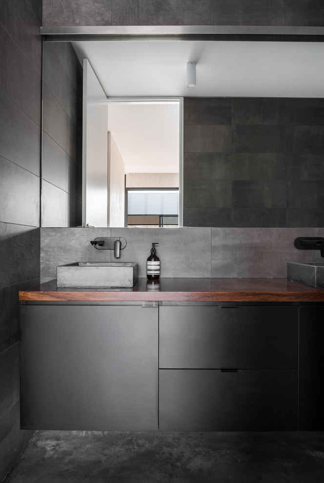 Industrial bathroom in Perth with black cabinets, gray tile, cement tile and wood benchtops.