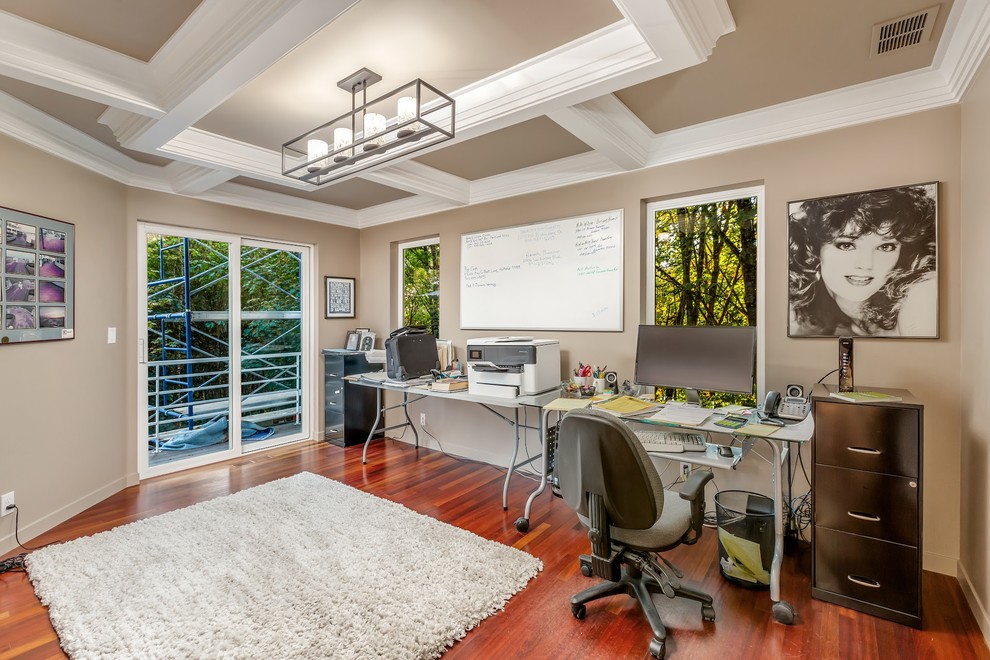 Diseño de despacho moderno pequeño con paredes beige, suelo de madera oscura, escritorio independiente y suelo multicolor