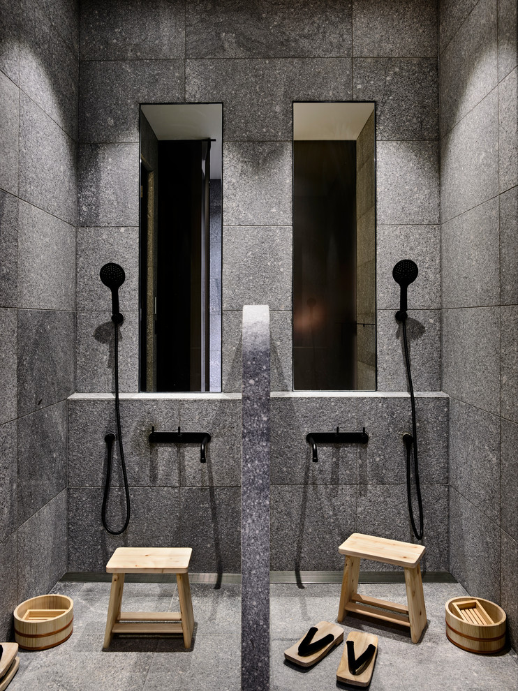 Modern bathroom with a curbless shower, gray tile, grey walls, grey floor and an open shower.