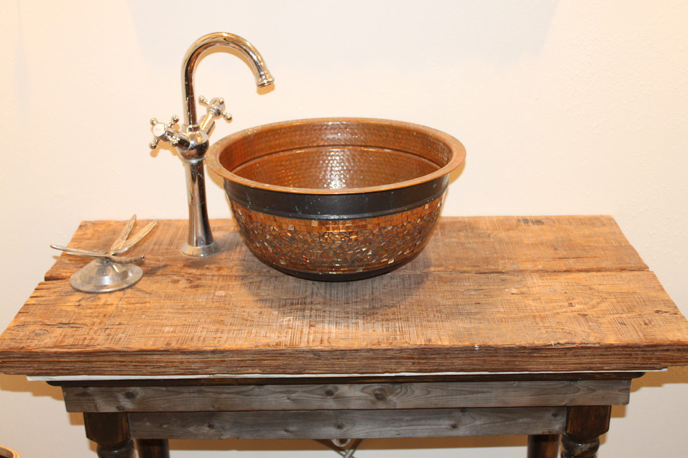 This is an example of a country bathroom in Austin with a vessel sink, furniture-like cabinets, wood benchtops, a claw-foot tub and a shower/bathtub combo.
