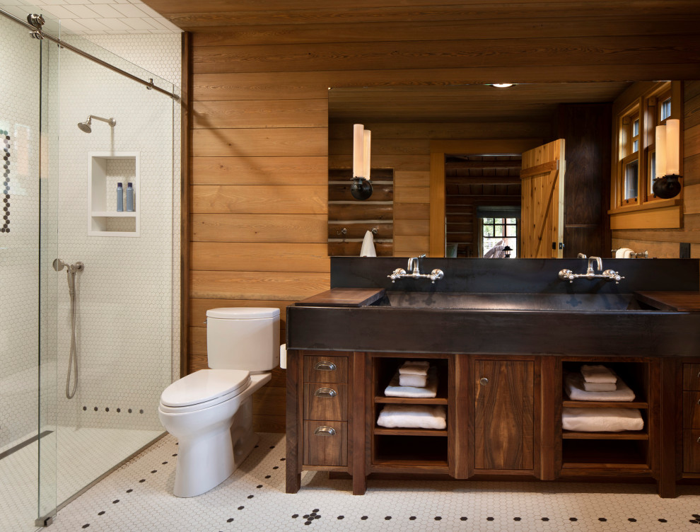 This is an example of a rustic bathroom in Other with a trough sink, double sinks, flat-panel cabinets, dark wood cabinets, an alcove shower, a two-piece toilet, white tiles, mosaic tiles, brown walls, mosaic tile flooring, white floors, a sliding door, black worktops, a wall niche, a freestanding vanity unit, a wood ceiling and wood walls.