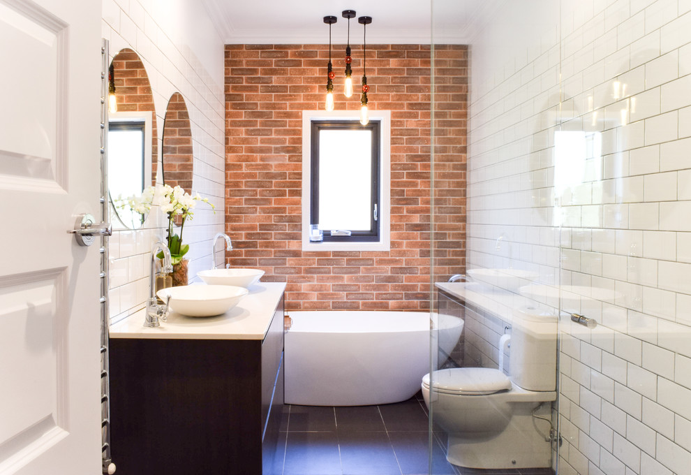 Mid-sized transitional master bathroom in Melbourne with flat-panel cabinets, dark wood cabinets, a freestanding tub, white tile, a vessel sink, engineered quartz benchtops, grey floor, a hinged shower door, a corner shower, a two-piece toilet, subway tile and white walls.