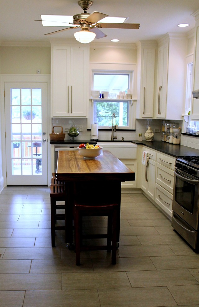 Small country l-shaped separate kitchen in New Orleans with a farmhouse sink, shaker cabinets, white cabinets, soapstone benchtops, white splashback, subway tile splashback, stainless steel appliances, ceramic floors, with island and grey floor.