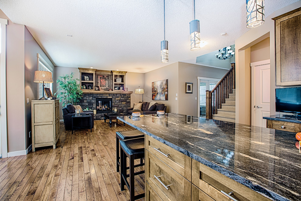 Eat-in kitchen - mid-sized rustic u-shaped medium tone wood floor and brown floor eat-in kitchen idea in Calgary with an undermount sink, shaker cabinets, medium tone wood cabinets, granite countertops, gray backsplash, glass tile backsplash, stainless steel appliances and an island