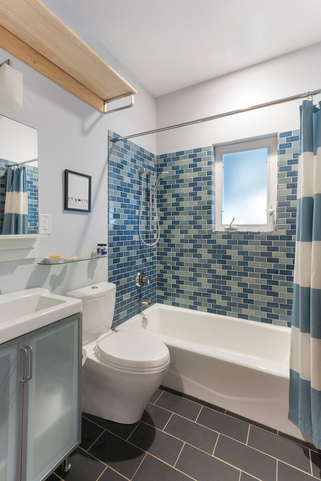 Inspiration for a contemporary bathroom in Austin with glass-front cabinets, an alcove tub, a shower/bathtub combo, a two-piece toilet, blue tile, subway tile, a console sink, blue walls and slate floors.