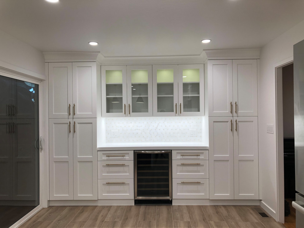 Eat-in kitchen - mid-sized transitional l-shaped medium tone wood floor and brown floor eat-in kitchen idea in San Francisco with a farmhouse sink, recessed-panel cabinets, white cabinets, quartz countertops, white backsplash, mosaic tile backsplash, stainless steel appliances, a peninsula and white countertops