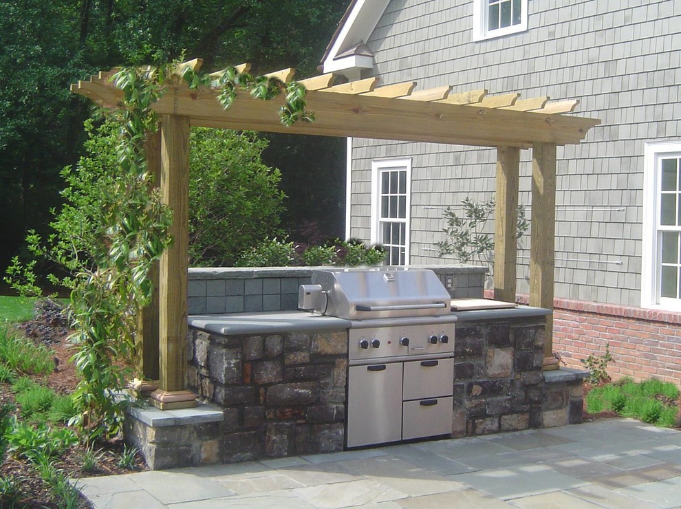 Mid-sized trendy side yard stone patio kitchen photo with a pergola
