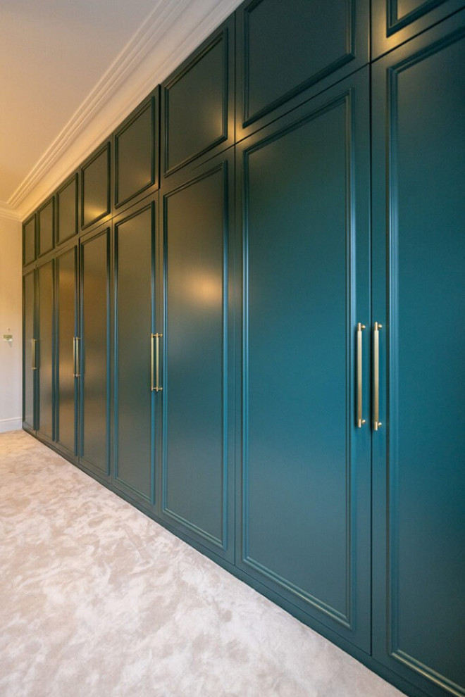 Design ideas for an expansive contemporary gender-neutral storage and wardrobe in London with beaded inset cabinets, green cabinets, carpet, brown floor and wood.