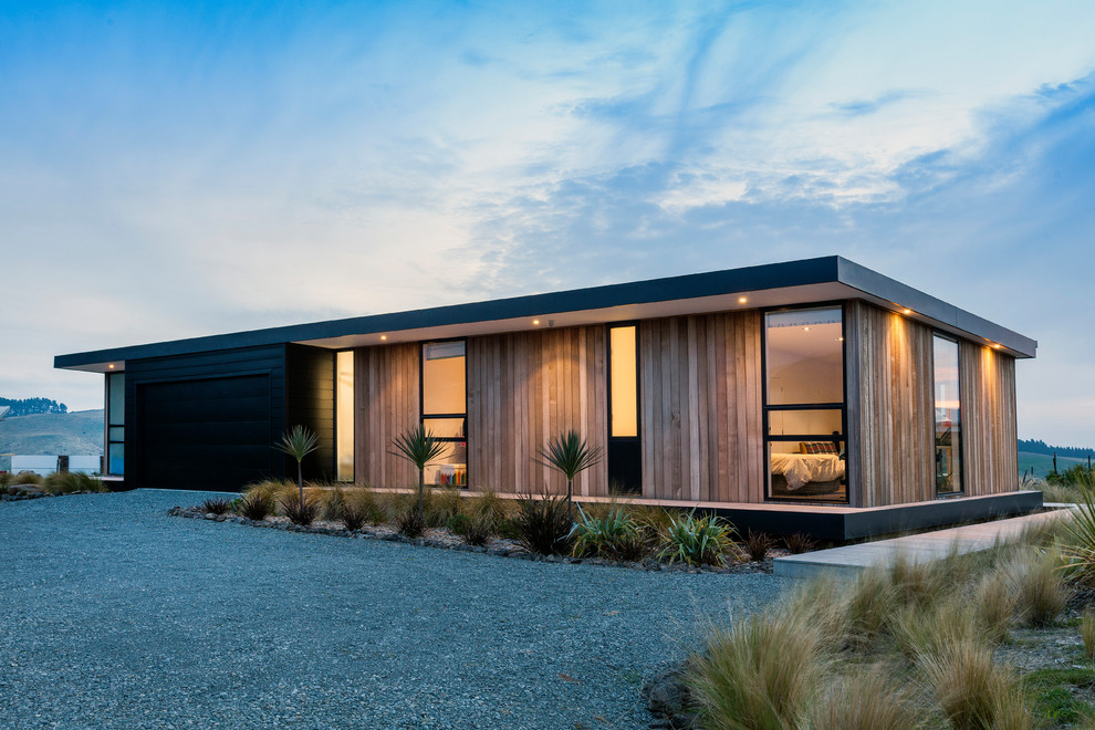 Photo of a Mid-sized contemporary One-storey Brown house exterior in Christchurch With Wood Siding, a Flat Roof and a Metal Roof.