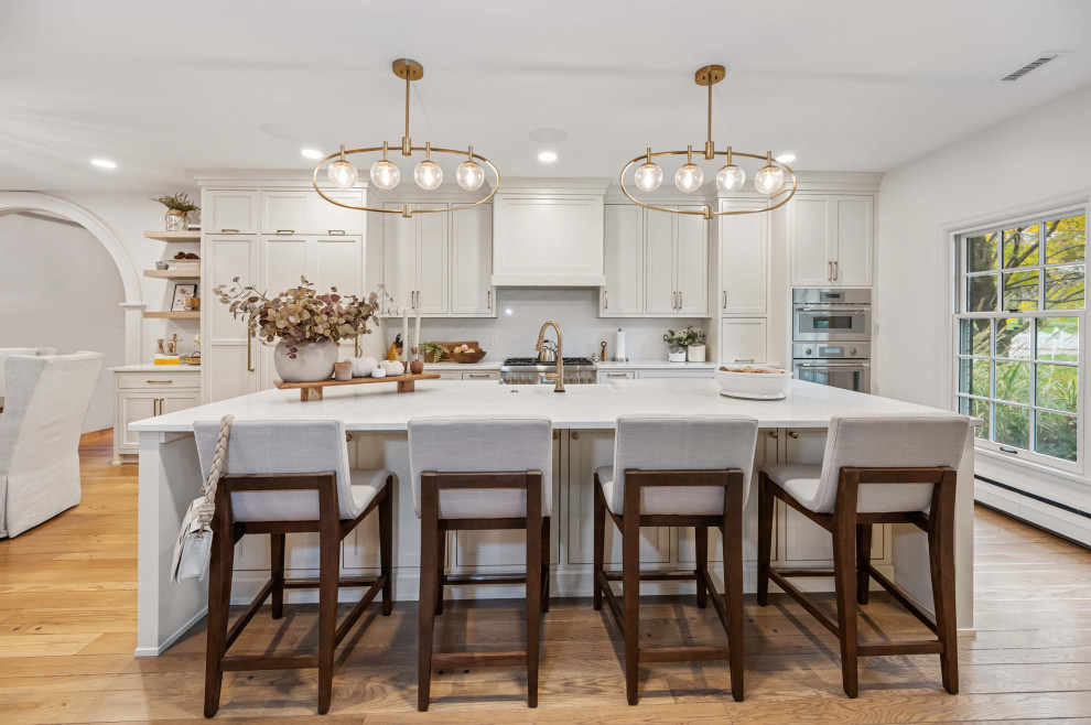 Large transitional galley light wood floor, beige floor and exposed beam eat-in kitchen photo in Cincinnati with an undermount sink, recessed-panel cabinets, beige cabinets, quartzite countertops, beige backsplash, quartz backsplash, stainless steel appliances, an island and beige countertops