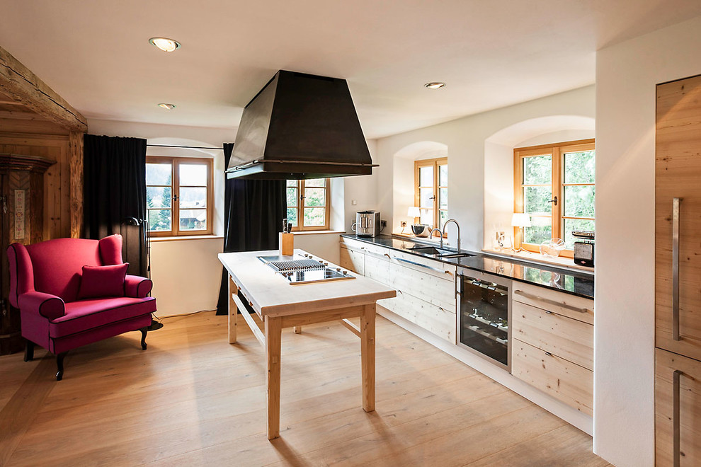 Mid-sized country kitchen in Stuttgart with flat-panel cabinets, light wood cabinets, white splashback, medium hardwood floors, with island and brown floor.