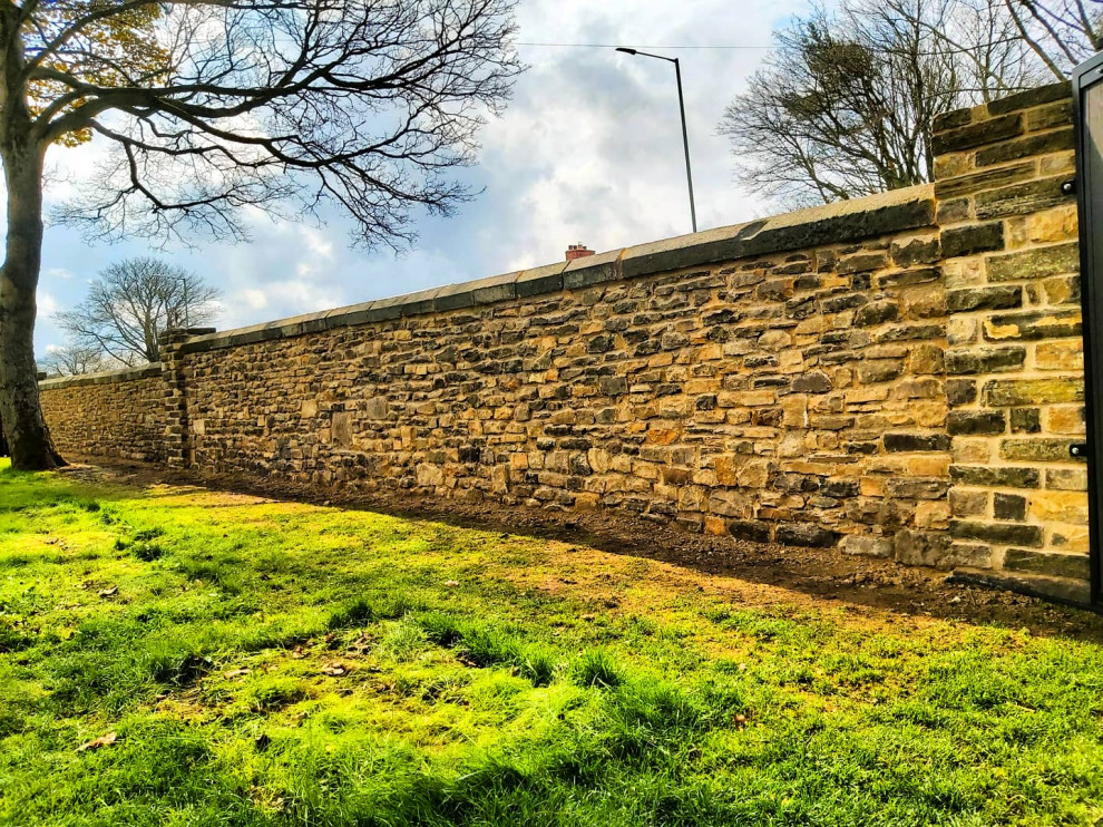 Design ideas for a mid-sized traditional front yard driveway in Other with a stone fence.