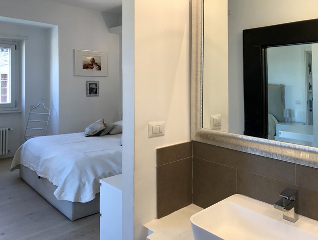 Immagine di una stanza da bagno padronale minimal di medie dimensioni con vasca da incasso, WC sospeso, piastrelle grigie, piastrelle in gres porcellanato, pareti bianche, parquet chiaro, lavabo rettangolare e top in cemento