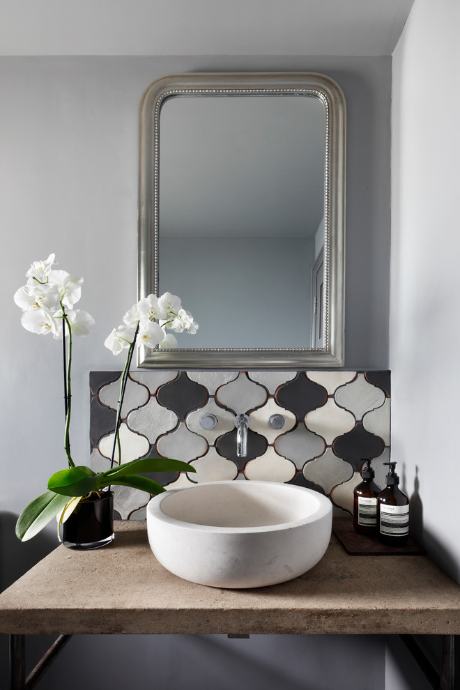 Design ideas for a small mediterranean powder room in London with ceramic tile, grey walls, concrete benchtops, furniture-like cabinets, grey cabinets, gray tile, a vessel sink and beige benchtops.