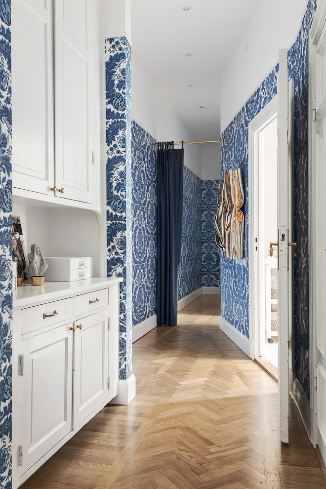 Inspiration for a mid-sized traditional hallway in Stockholm with blue walls and light hardwood floors.