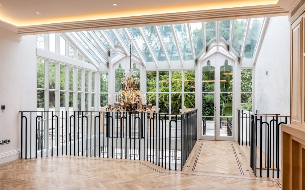 This is an example of a large eclectic sunroom in London with light hardwood floors, no fireplace, a glass ceiling and brown floor.
