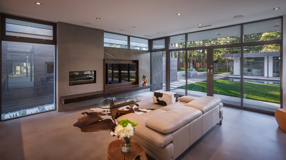 This is an example of a large contemporary enclosed family room in San Francisco with white walls, concrete floors, a standard fireplace, a stone fireplace surround and a wall-mounted tv.