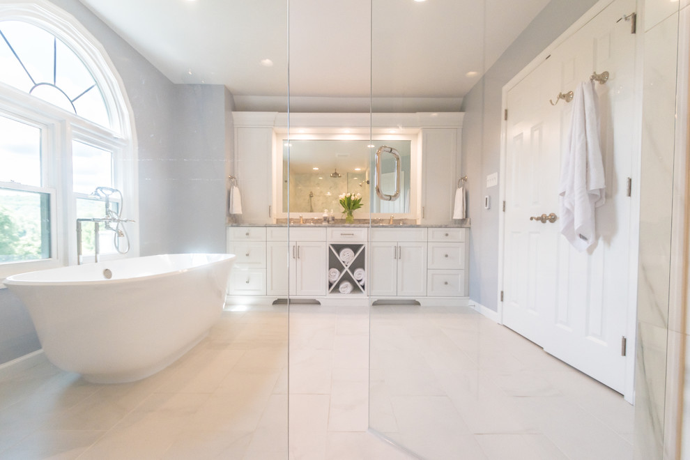 Photo of a mid-sized traditional master bathroom in Philadelphia with white cabinets, a freestanding tub, porcelain tile, quartzite benchtops, flat-panel cabinets, an open shower, a one-piece toilet, white tile, blue walls, porcelain floors, an undermount sink, white floor and a hinged shower door.
