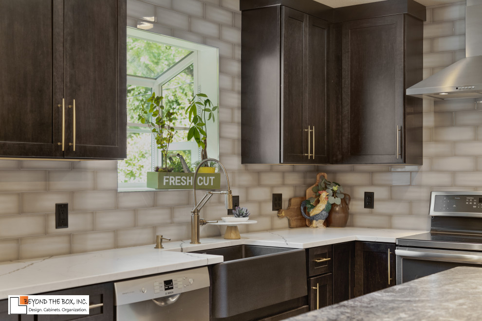 Inspiration for a mid-sized transitional l-shaped medium tone wood floor and brown floor kitchen remodel with a farmhouse sink, shaker cabinets, black cabinets, granite countertops, gray backsplash, ceramic backsplash, stainless steel appliances, an island and white countertops