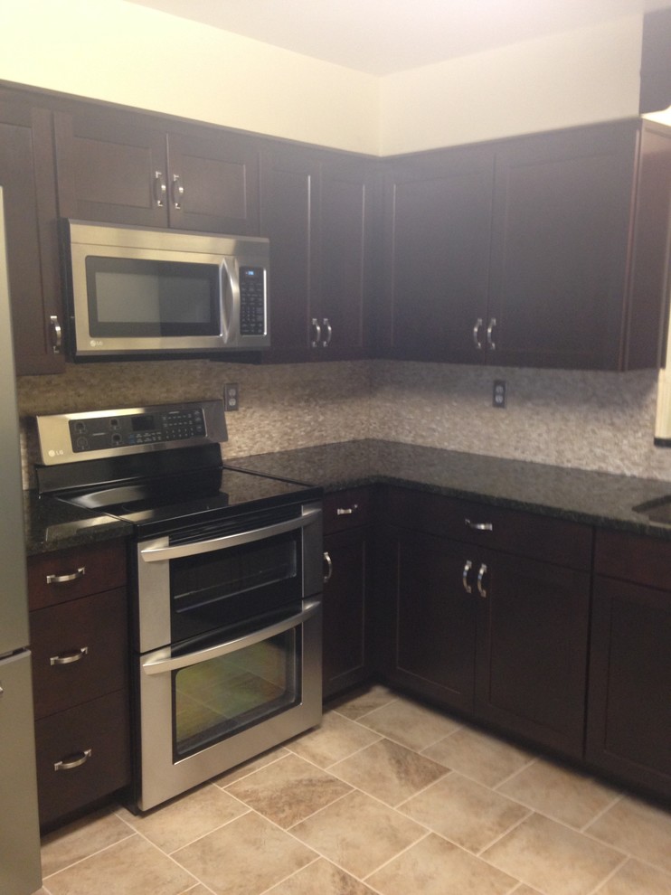 Enclosed kitchen - mid-sized transitional l-shaped porcelain tile enclosed kitchen idea with an undermount sink, shaker cabinets, dark wood cabinets, granite countertops, beige backsplash, stone tile backsplash, stainless steel appliances and an island