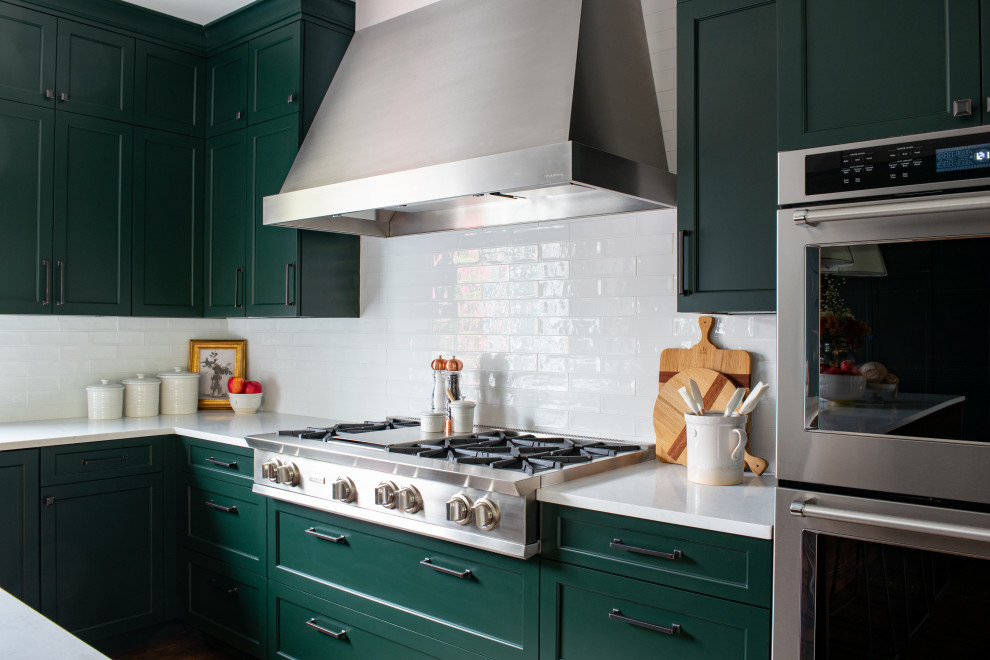 シアトルにある高級な中くらいなトランジショナルスタイルのおしゃれなキッチン (エプロンフロントシンク、シェーカースタイル扉のキャビネット、緑のキャビネット、クオーツストーンカウンター、白いキッチンパネル、サブウェイタイルのキッチンパネル、パネルと同色の調理設備、濃色無垢フローリング、茶色い床、緑のキッチンカウンター) の写真