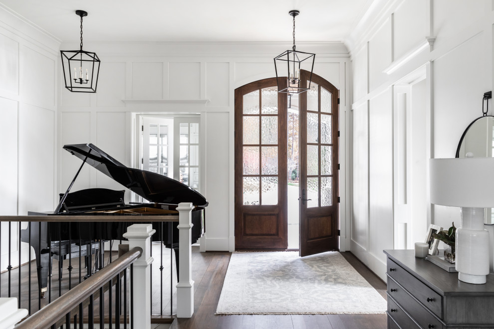Photo of a beach style foyer in Charlotte with white walls, dark hardwood floors, a double front door, a dark wood front door, brown floor and panelled walls.