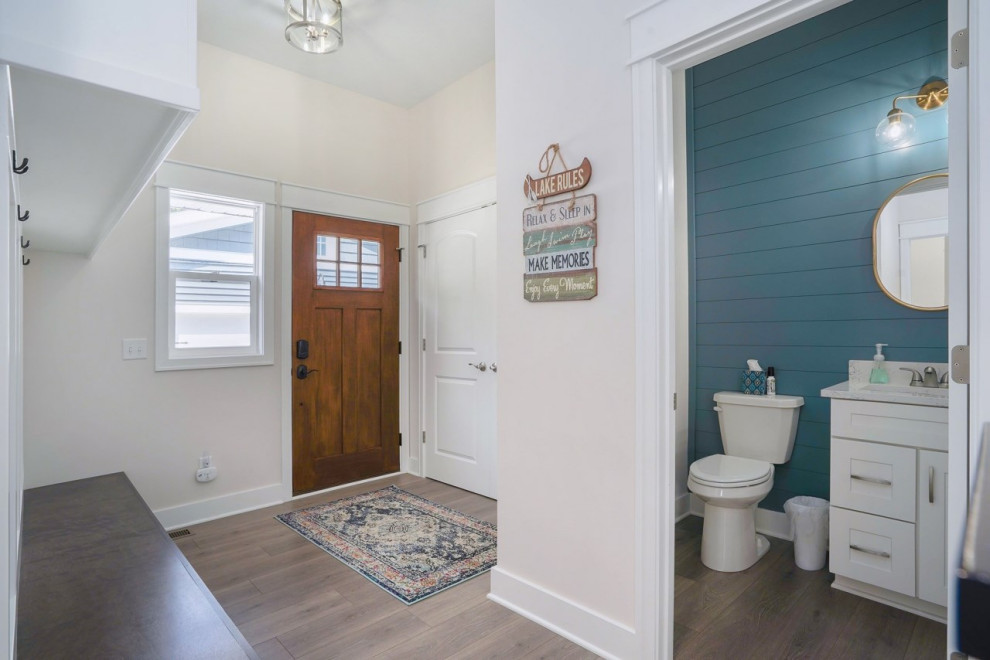 Inspiration for a small traditional powder room in Grand Rapids with recessed-panel cabinets, white cabinets, blue walls, vinyl floors, an integrated sink, white benchtops and a freestanding vanity.