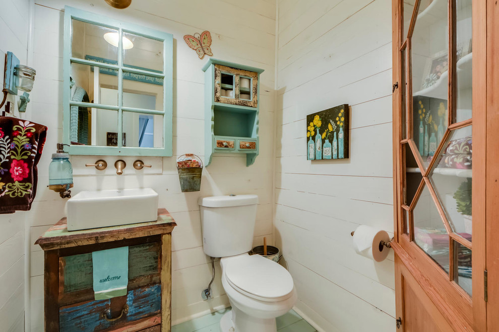 Inspiration for a small country powder room in Austin with a vessel sink, furniture-like cabinets, distressed cabinets, wood benchtops, a two-piece toilet, white walls, painted wood floors and brown benchtops.