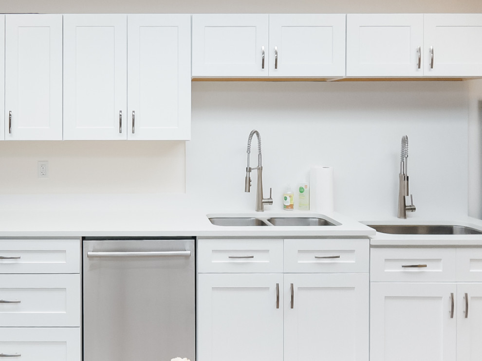 Inspiration for a mid-sized modern galley eat-in kitchen in Seattle with an undermount sink, shaker cabinets, white cabinets, laminate benchtops, white splashback, stone slab splashback, stainless steel appliances, vinyl floors, with island, brown floor, white benchtop and timber.