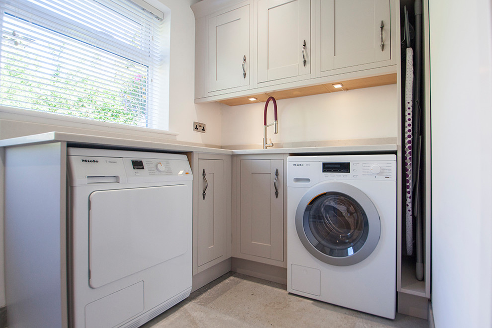Design ideas for a large transitional u-shaped laundry room in Wiltshire with grey cabinets, quartzite benchtops, stone slab splashback, light hardwood floors and brown floor.