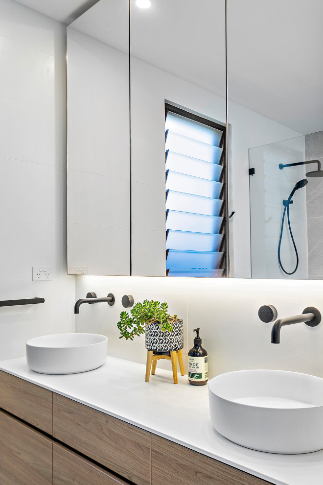 This is an example of a mid-sized contemporary master bathroom in Wollongong with flat-panel cabinets, white tile, porcelain tile, white walls, a vessel sink, white benchtops, a double vanity, a built-in vanity and medium wood cabinets.