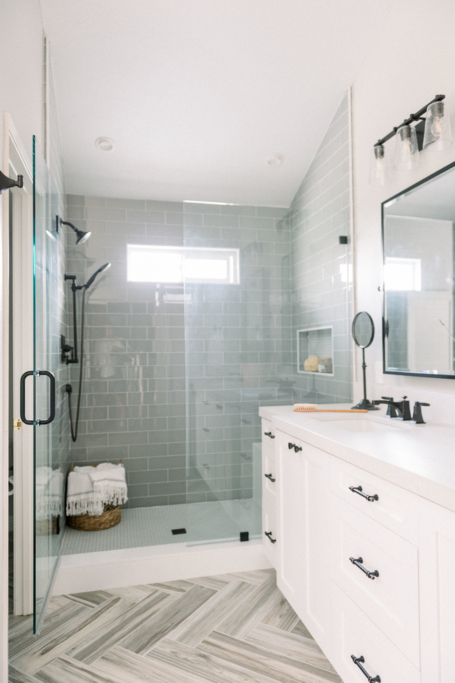 This is an example of a mid-sized country master bathroom in San Diego with shaker cabinets, white cabinets, an alcove shower, a one-piece toilet, gray tile, glass tile, grey walls, porcelain floors, an undermount sink, engineered quartz benchtops, beige floor, a hinged shower door and white benchtops.
