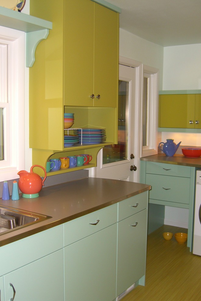 Inspiration for a mid-sized midcentury galley separate kitchen in Portland with a drop-in sink, flat-panel cabinets, green cabinets, laminate benchtops, metallic splashback, stainless steel appliances, vinyl floors and no island.