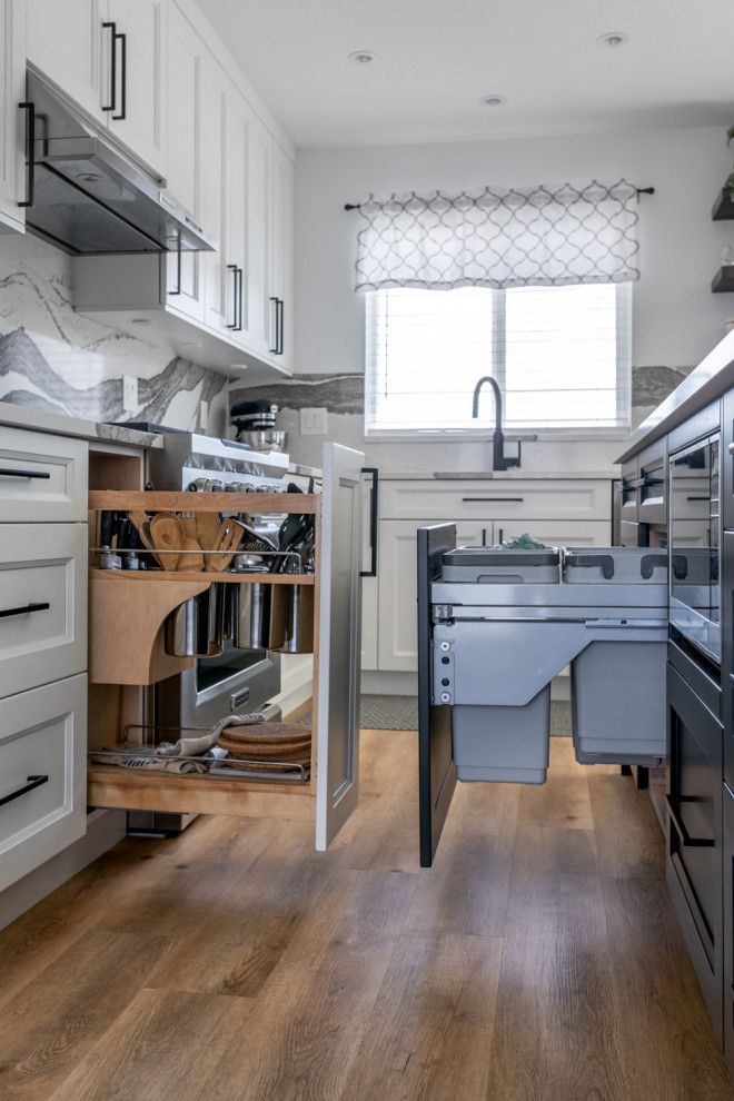 Inspiration for a mid-sized transitional u-shaped medium tone wood floor and brown floor eat-in kitchen remodel with an undermount sink, recessed-panel cabinets, white cabinets, quartz countertops, white backsplash, stone slab backsplash, stainless steel appliances, an island and white countertops
