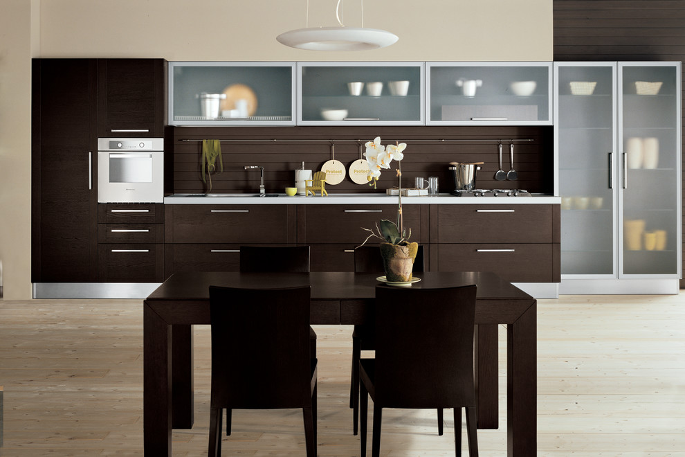 Eat-in kitchen - mid-sized modern single-wall light wood floor eat-in kitchen idea with a double-bowl sink, glass-front cabinets, dark wood cabinets, solid surface countertops, brown backsplash, stainless steel appliances and no island