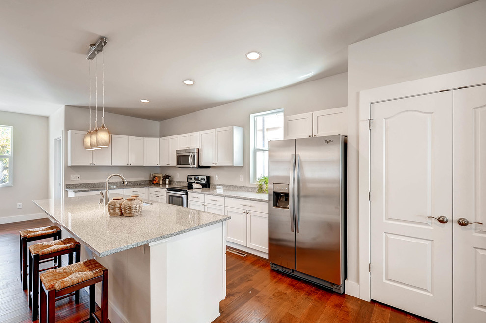 Inspiration for a medium tone wood floor and brown floor kitchen remodel in Denver with an undermount sink, shaker cabinets, white cabinets, granite countertops, stainless steel appliances and an island