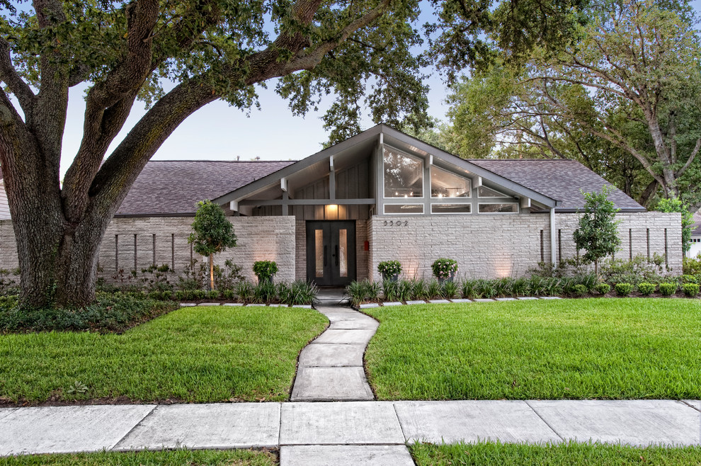 Inspiration for a mid-sized midcentury one-storey brick beige house exterior in Houston with a gable roof and a shingle roof.