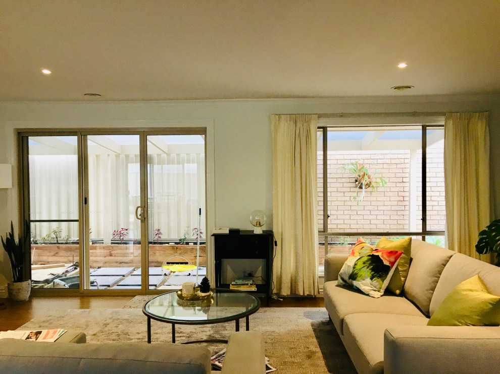 Design ideas for a mid-sized modern open concept family room in Melbourne with beige walls and a freestanding tv.