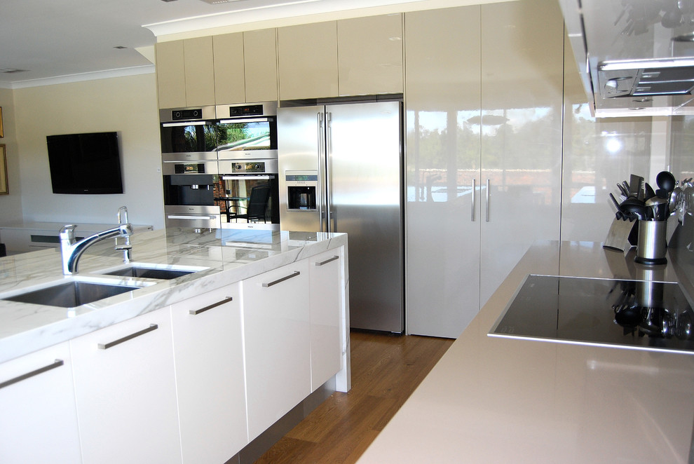 Design ideas for a large contemporary l-shaped kitchen pantry in Sydney with an undermount sink, flat-panel cabinets, green cabinets, marble benchtops, green splashback, glass sheet splashback, stainless steel appliances, medium hardwood floors and with island.