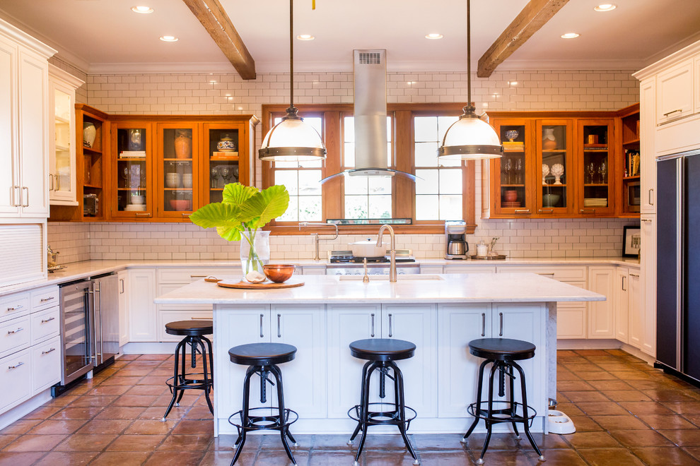 Inspiration for a large industrial u-shaped open plan kitchen in New Orleans with quartz benchtops, white splashback, subway tile splashback, terra-cotta floors, with island, an undermount sink, recessed-panel cabinets, white cabinets, stainless steel appliances, orange floor, white benchtop and exposed beam.