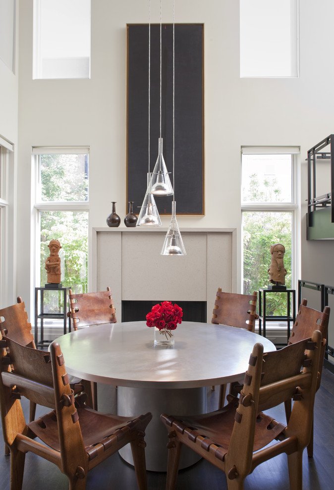 Inspiration for an eclectic dining room in Chicago with white walls, dark hardwood floors and a standard fireplace.