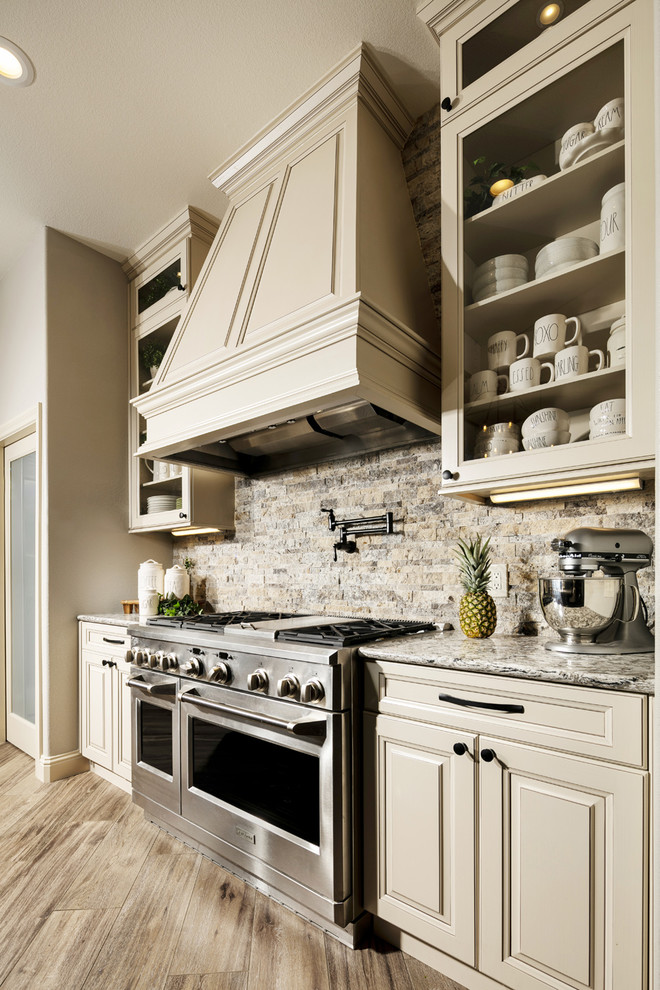 Inspiration for a large transitional l-shaped porcelain tile and brown floor eat-in kitchen remodel in Orlando with an undermount sink, raised-panel cabinets, beige cabinets, quartz countertops, multicolored backsplash, travertine backsplash, stainless steel appliances, an island and multicolored countertops